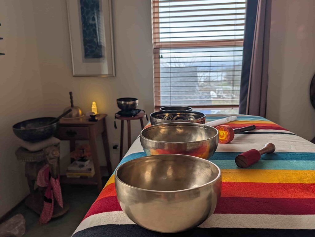 A row of Tibetan healing singing bowls sits on a massage table.