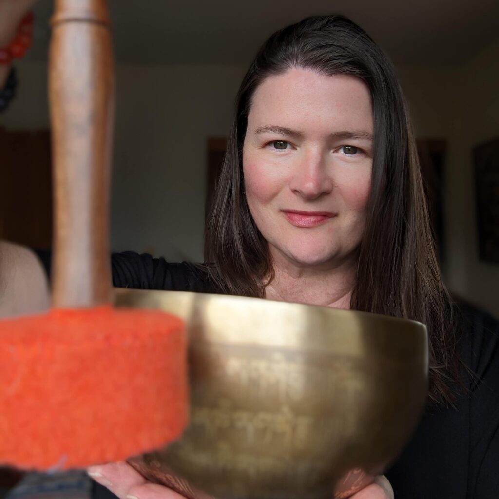 Lara from sound healing therapy with Lara strikes a healing Tibetan singing bowl.