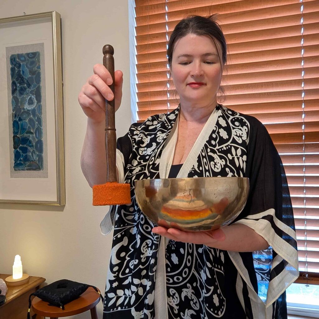 Sound healing practitioner Lara Dunning playing a Tibetan singing bowl in her Anacortes healing room