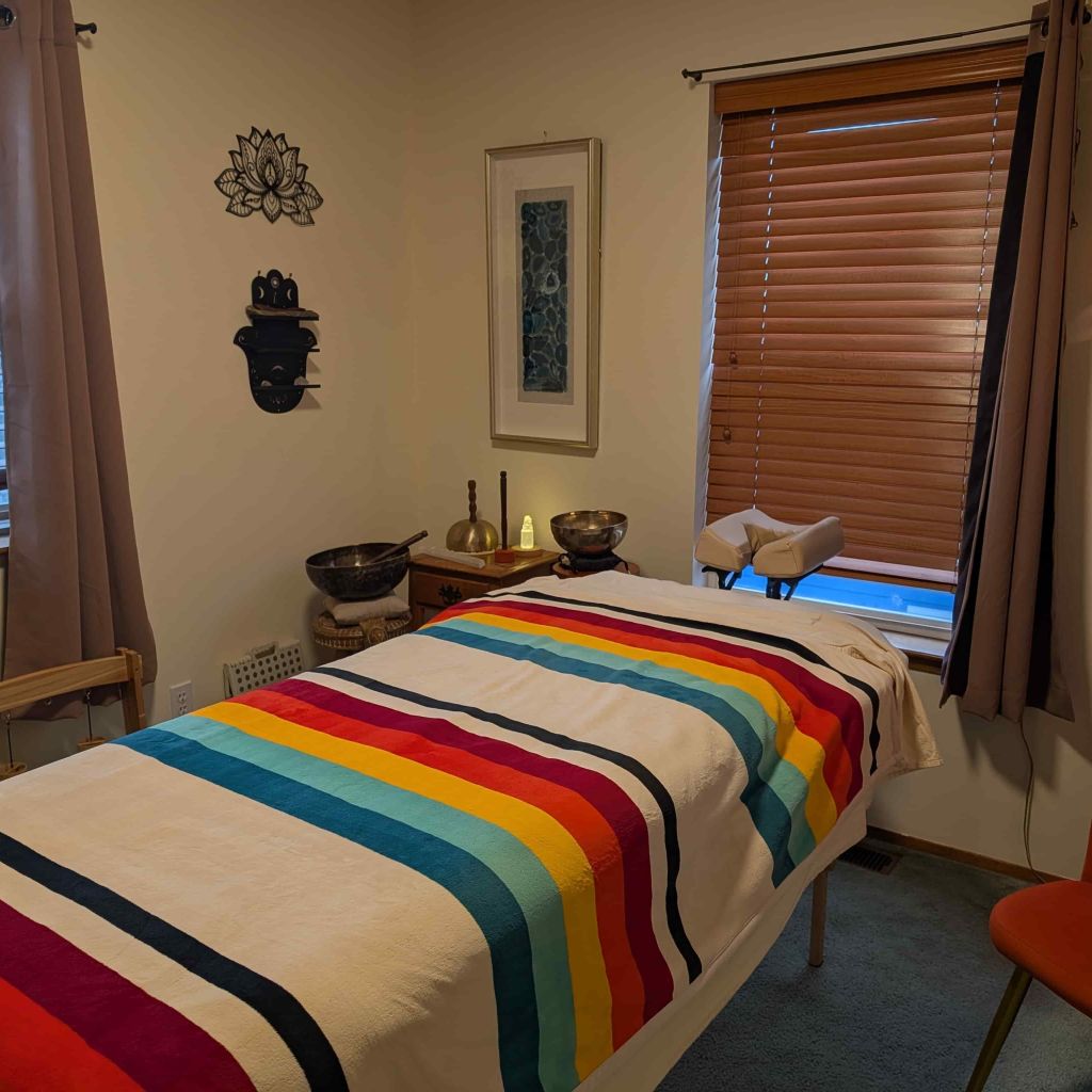Private sound healing room in Anacortes with a treatment table, Tibetan singing bowls, and a striped blanket