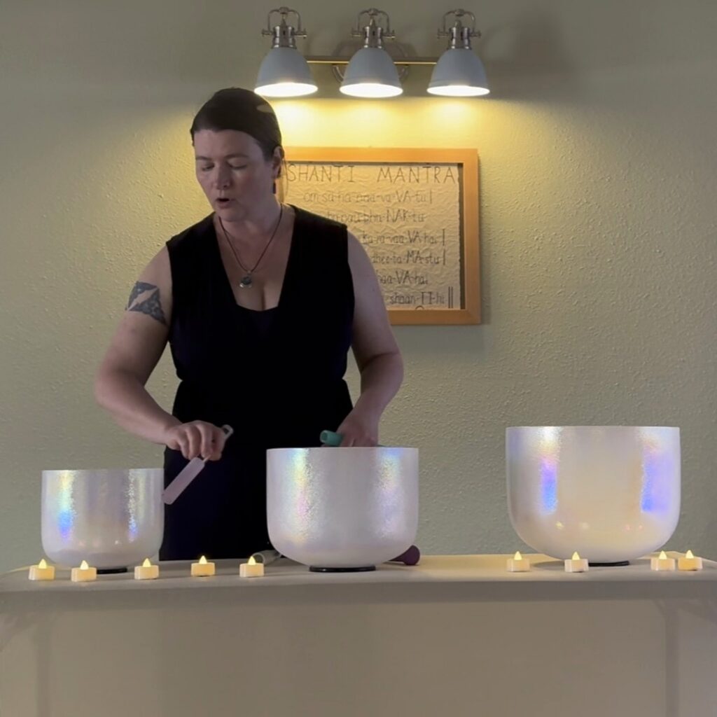 Lara Dunning playing crystal singing bowls while leading a Tone Circle group vocal toning gathering